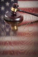 Wooden gavel resting on american flag reflecting table