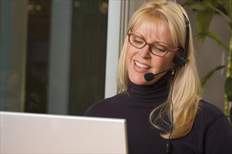 Attractive businesswoman smiles as she talks on her phone headset