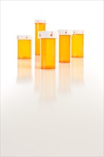 Several different sized empty medicine bottles on reflective surface