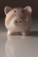 Piggy bank with bandage on face on gradated background