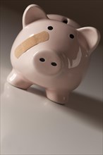 Piggy bank with bandage on face on gradated background