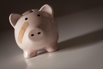 Piggy bank with bandage on face on gradated background