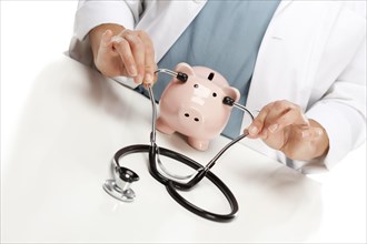 Female doctor holding stethoscope to the ears of A pink piggy bank abstract