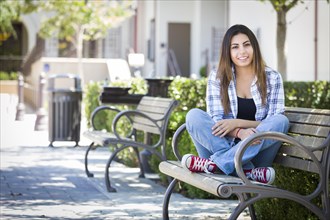 Happy mixed-race female student portrait on school campus bench
