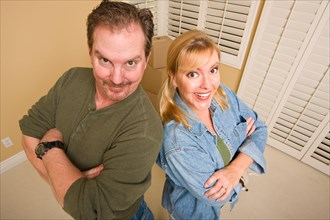 Smiling goofy couple and moving boxes in empty room