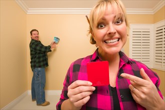 Fun happy couple comparing paint colors in empty room