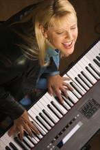 Female musician sings while playing digital piano