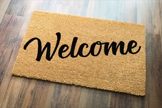Tan welcome mat on wood floor background