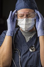 Grimacing female doctor or nurse wearing protective facial wear and surgical gloves