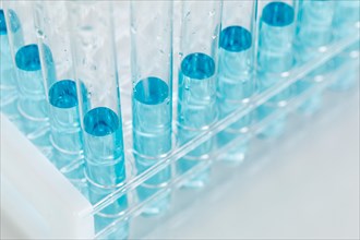 Abstract of scientific test tubes containing blue chemical in rack