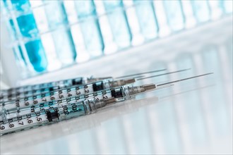 Abstract of scientific needle syringes and test tubes containing blue chemical in rack