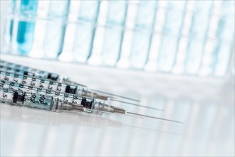 Abstract of scientific needle syringes and test tubes containing blue chemical in rack