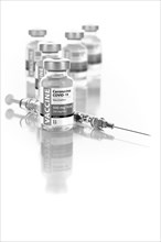 Coronavirus COVID-19 vaccine vials and syringe on reflective surface