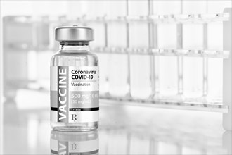 Coronavirus COVID-19 vaccine vial near test tubes on reflective surface