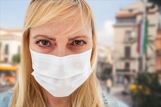 Sick infected young woman wearing face mask walks on street in Italy