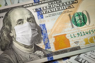 One hundred dollar bill with medical face mask on face of benjamin franklin