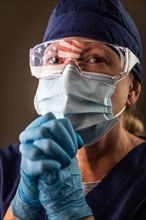 American flag reflecting on distressed praying female medical worker wearing protective face mask and goggles