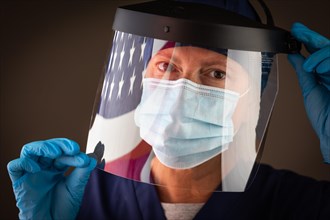 American flag reflecting on female medical worker wearing protective face mask and shield