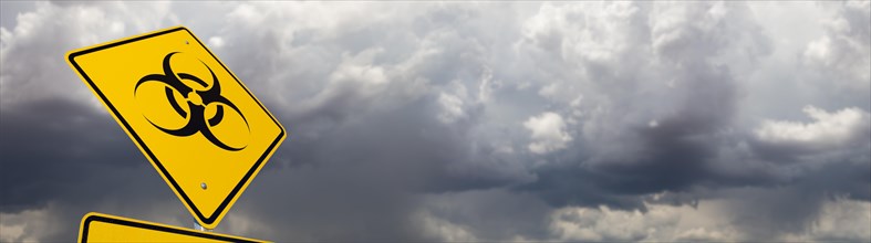 Bio-hazard yellow road sign against ominous stormy cloudy sky banner