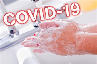 Woman thoroughly washing hands in the sink basin with COVID-19 coronavirus text
