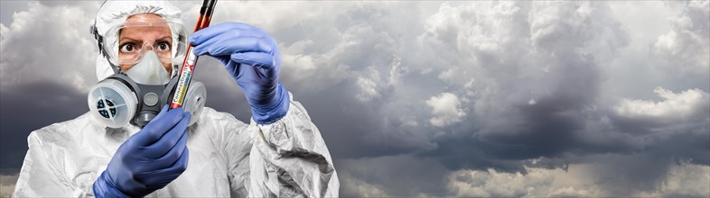 Female doctor or nurse in hazmat gear holding positive coronavirus test tube cloudy sky banner