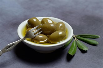 Green olives in bowl with olive oil
