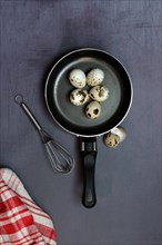 Quail eggs in frying pan and whisk