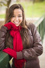 Pretty festive smiling woman portrait wearing a red scarf and mittens outside