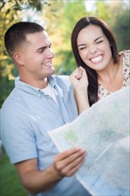 Happy mixed-race couple looking over A map outside together