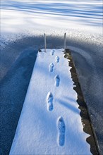 Footprints on jetty in snow