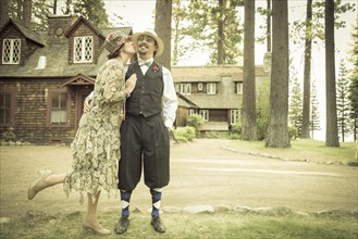 Attractive 1920s dressed romantic couple in front of old cabin portrait