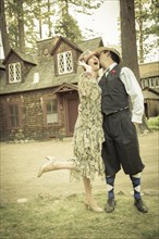 Attractive 1920s dressed romantic couple in front of old cabin portrait