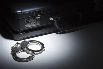 Pair of handcuffs and briefcase under spot light abstract