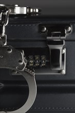 Pair of handcuffs on briefcase with the numbers 911 on lock