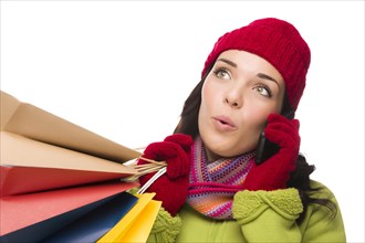mixed-race woman wearing winter clothing holding shopping bags talking on cell phone looking up and to side isolated on white