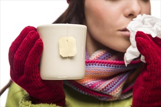 Young sick woman with tissue holding cup with blank tea bag hanging