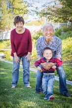 Happy chinese grandparents having fun with their mixed race grandson outside