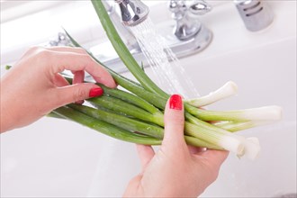 Woman washing onions in the kitchen sink