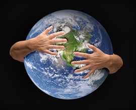 Human arms embracing and nurturing the planet earth