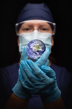 Nurse or doctor wearing face mask and surgical gloves holding the planet earth