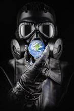 Menacing entity wearing fallout gas mask threatening planet earth with gloved hand
