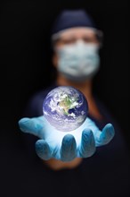 Nurse or doctor wearing face mask and surgical gloves with palm under the floating planet earth