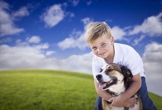 Handsome young boy playing with his dog on a lush green grass field