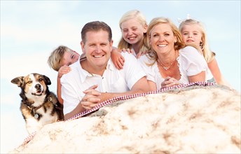 Happy caucasian family and dog portrait at the beach one sunny afternoon