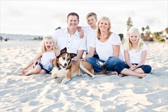Happy caucasian family and their dog at the beach