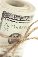 Roll of one hundred dollar bills tied in burlap string isolated on a white background