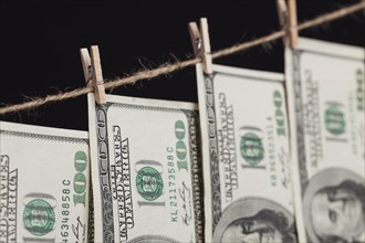Hundred dollar bills hanging from a clothesline on a dark background