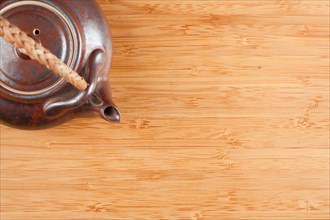 Tea pot and bamboo textured surface background with plenty of room for text