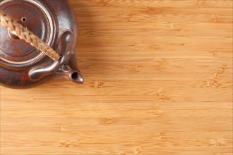 Tea pot and bamboo textured surface background with plenty of room for text