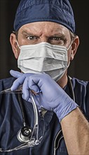 Determined looking male doctor or nurse with protective wear and stethoscope